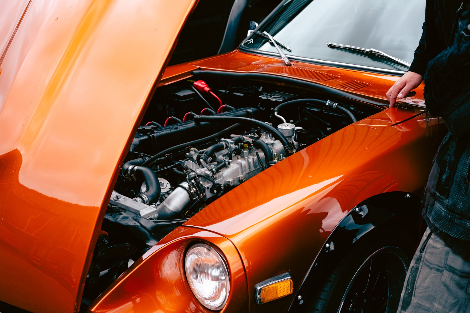 An orange car with its bonnet up.