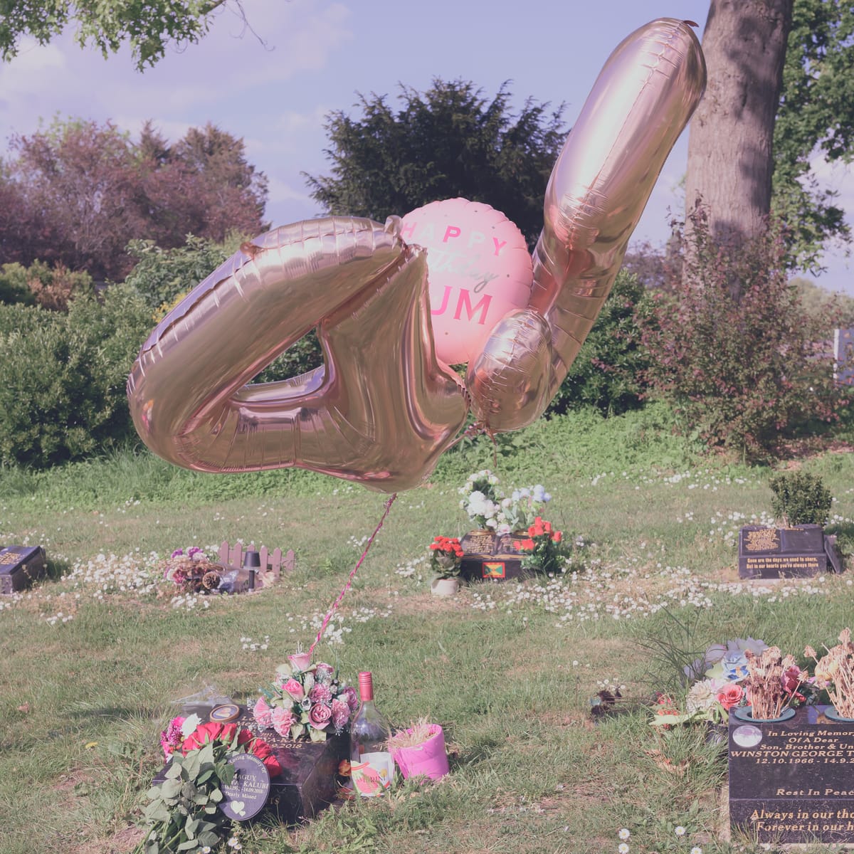 Balloons billowing over a grave.