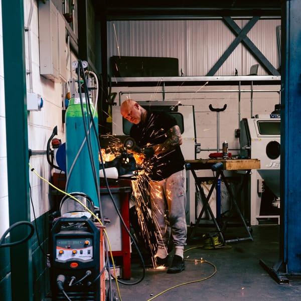 A mechanic angle grinding a part.